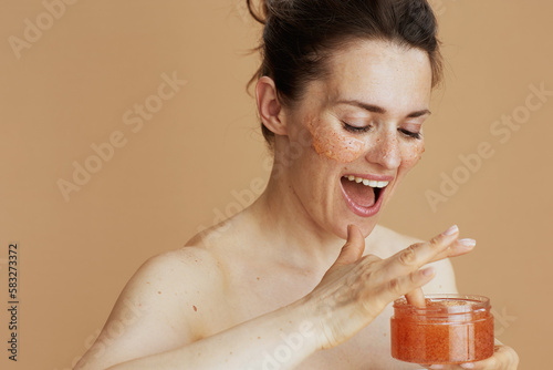 happy modern woman with face scrub isolated on beige photo