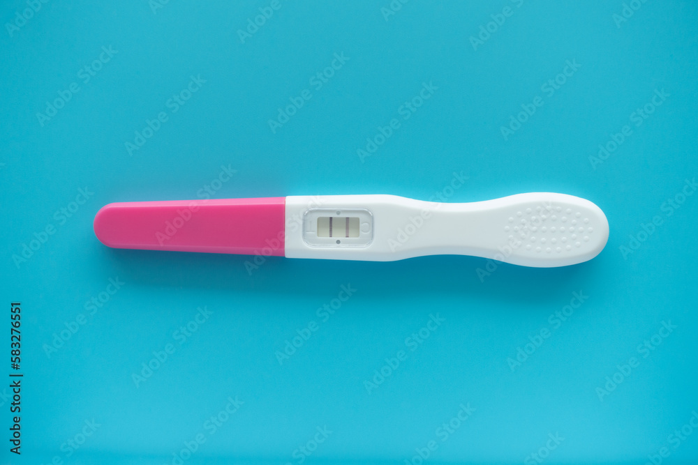 White Plastic Pregnancy test positive with two stripes results isolated on Pastel light blue background. Closeup. Top down view. White Plastic Pregnancy test positive with two stripes results isolated on Pastel light blue background. Closeup. Top down view.