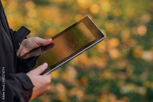 close-up boy with tablet near school with online learning book, tablet in child's hands, schoolgirl, on beautiful yellow-green background, blurred background behind, bokeh, online education, side