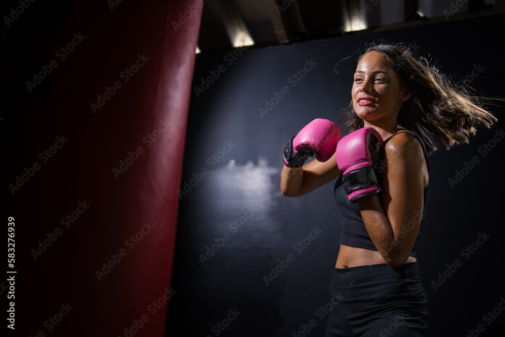 Dark Haired Girl Boxing a Punching Bag in a Moody Setting