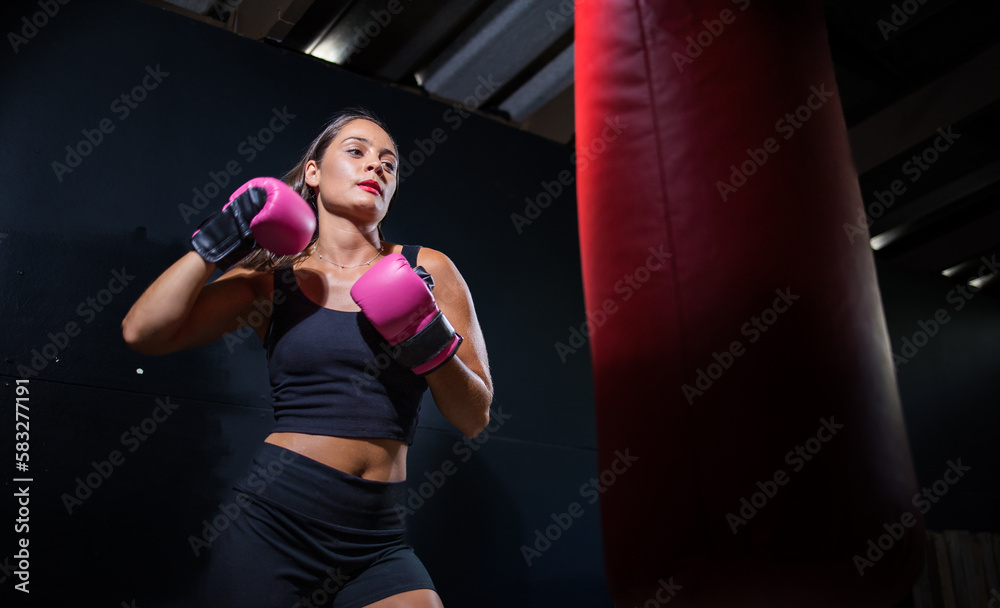 Dark Haired Girl Boxing a Punching Bag in a Moody Setting