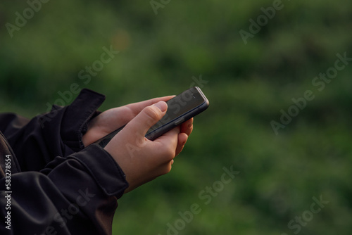 boy with tablet near school with online textbook, phone in child's hands, schoolgirl, on beautiful green background, blurred background behind, bokeh, online education, side view. 