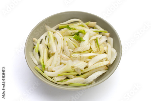 Sliced fresh fennel in bowl on yellow background.