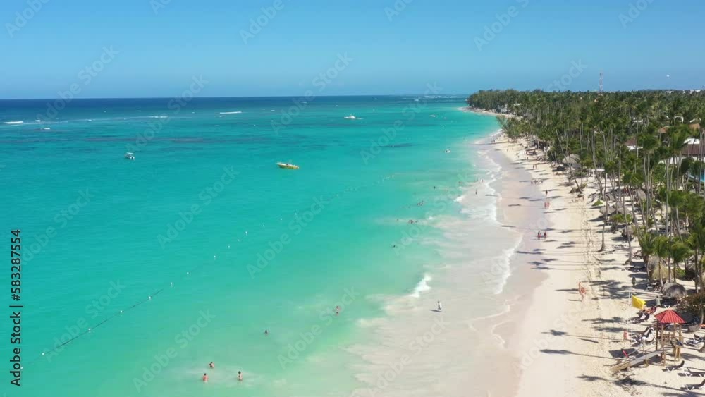Tropical coastline with resorts, palm trees, caribbean sea and people having fun on beach. Travel destinations. Dominican Republic. Aerial view Tropical coastline with resorts, palm trees, caribbean sea and people having fun on beach. Travel destinations. Dominican Republic. Aerial view