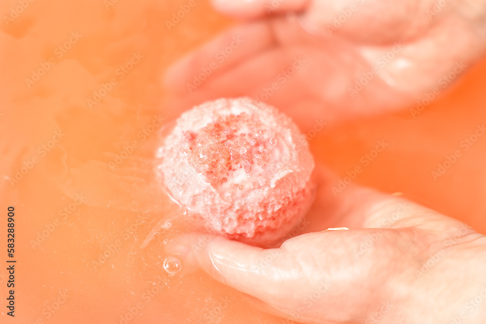 Fototapeta premium Woman putting bath bomb into water in room, closeup
