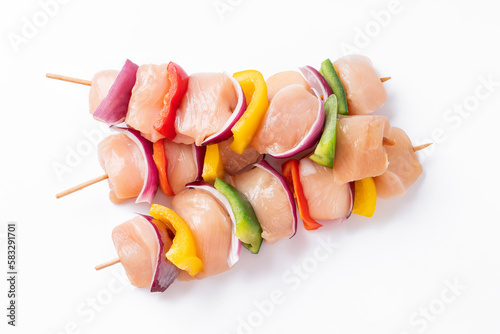 Uncooked mixed meat skewer with peppers.Raw chicken skewers with vegetables, peppers, onions, on a white background.Skewers with pieces of raw meat, red, yellow and green pepper.Top view. photo