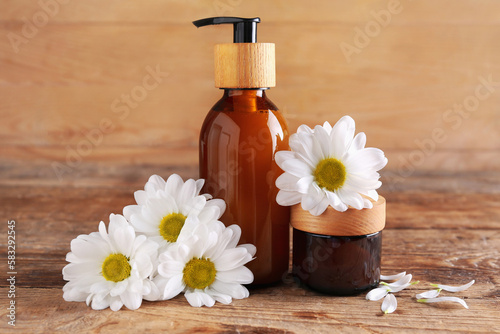 Natural cosmetic products and chamomile flowers on wooden background