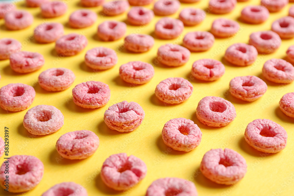 Many pink cereal rings on yellow background Many pink cereal rings on yellow background