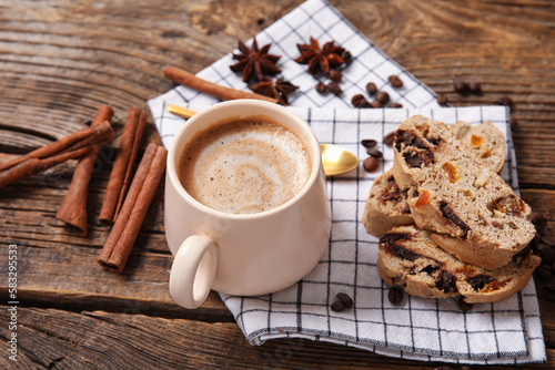 Delicious biscotti cookies, cinnamon, beans and cup of coffee on wooden background