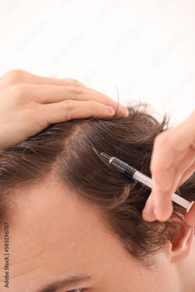 Young man with hair loss problem making injection in bathroom, closeup Young man with hair loss problem making injection in bathroom, closeup