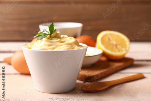 Bowl with tasty mayonnaise sauce and ingredients on wooden table