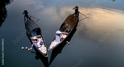 Two Vietnamese girls with wihte tradition Ao Dai are lighting candle in lantern to pray in the river in Hue City, Vietnam - Ao dai is famous traditional costume for the women in Vietnam.
