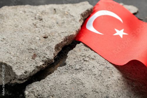 Stone debris with Turkish flag on dark background, closeup. Turkey earthquake concept