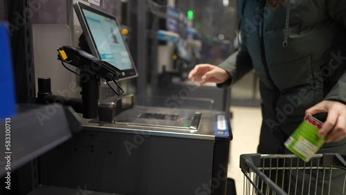 the girl scans the goods at the self-service checkout and pays for the purchase using the phone