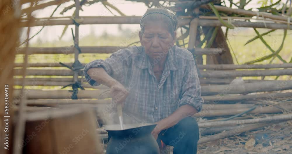 Asian rural life in the morning which is a poor farmer woman and employee in the farm, cooking for her breakfast using a stove with firewood, boiling steam and smoke from firewood. Asian rural life in the morning which is a poor farmer woman and employee in the farm, cooking for her breakfast using a stove with firewood, boiling steam and smoke from firewood.