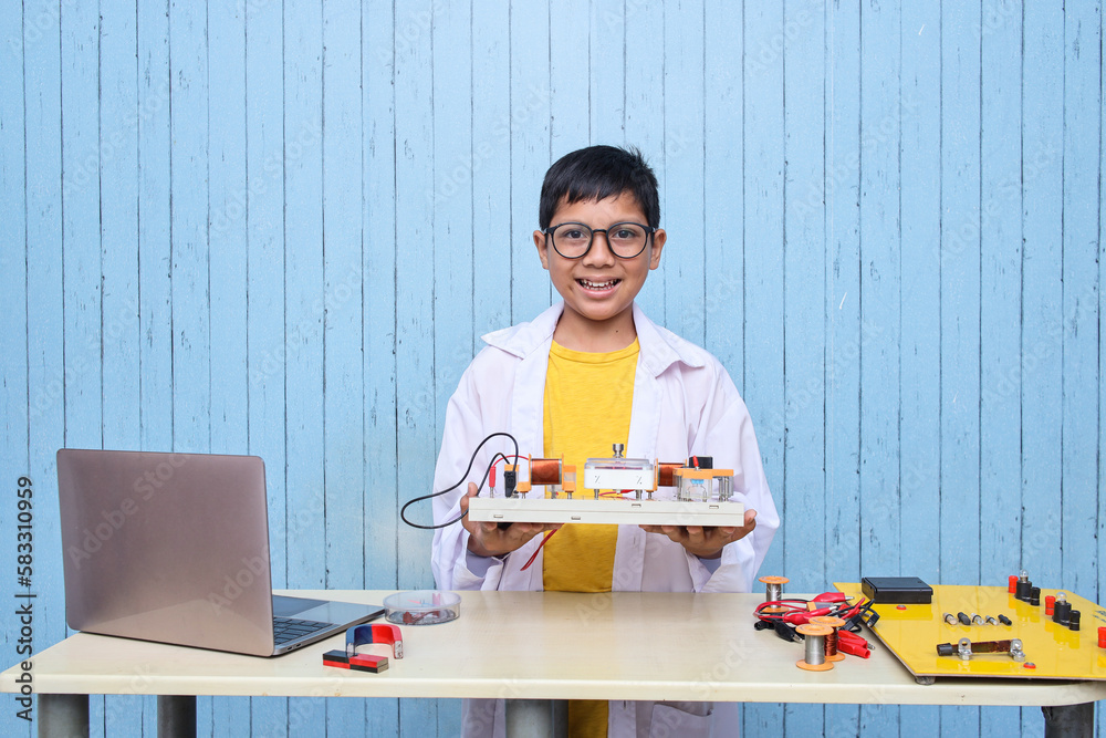 Smart looking Asian boy working with circuits, wires, computer, motor on his project. Science, Technology, Engineering and Mathematics (STEM) education concept. Smart looking Asian boy working with circuits, wires, computer, motor on his project. Science, Technology, Engineering and Mathematics (STEM) education concept.