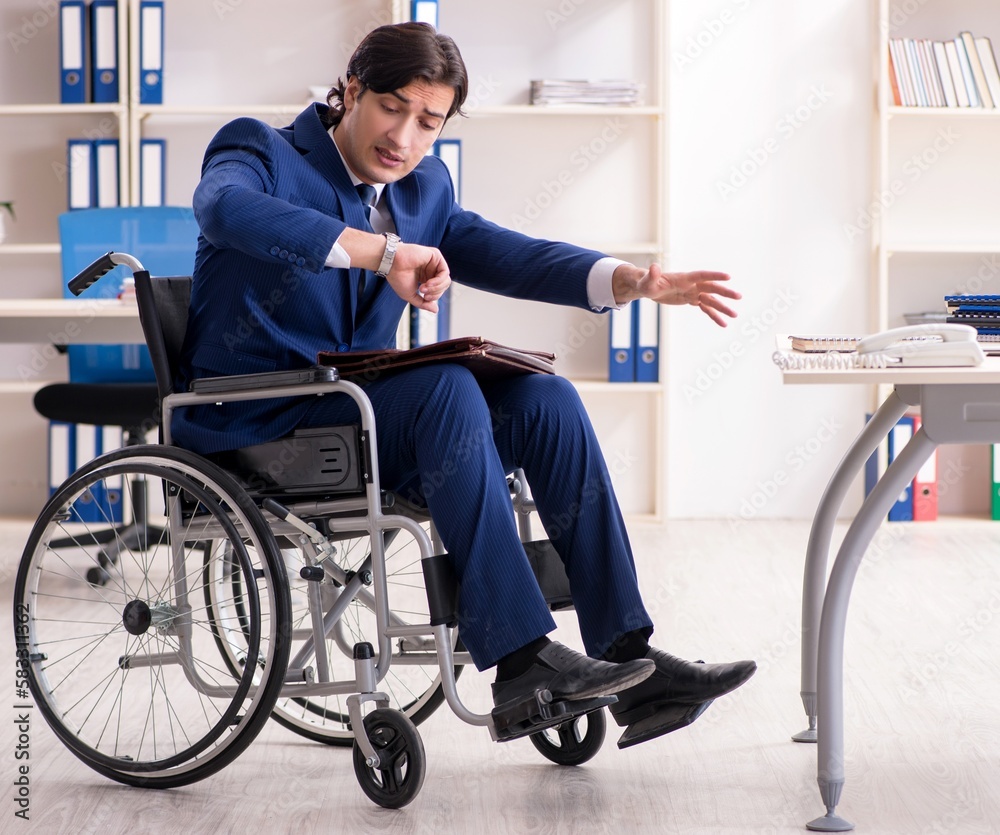 Young male employee in wheelchair working in the office Young male employee in wheelchair working in the office