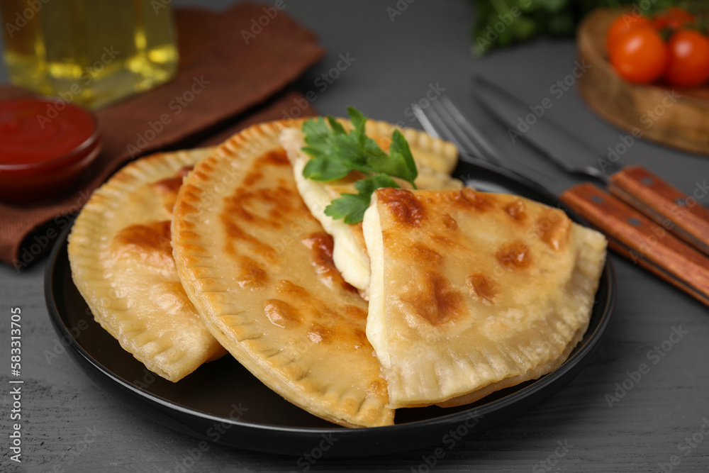 Delicious fried chebureki with cheese and parsley on grey wooden table Delicious fried chebureki with cheese and parsley on grey wooden table