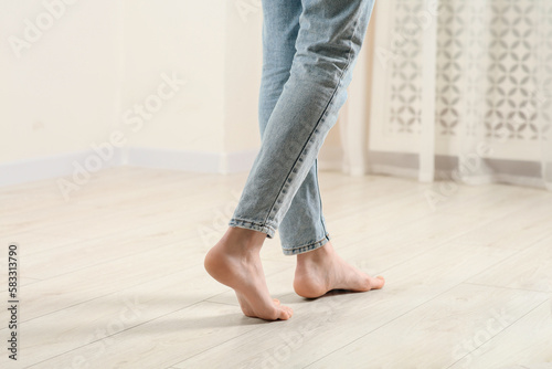 Woman stepping barefoot in room at home, closeup. Floor heating