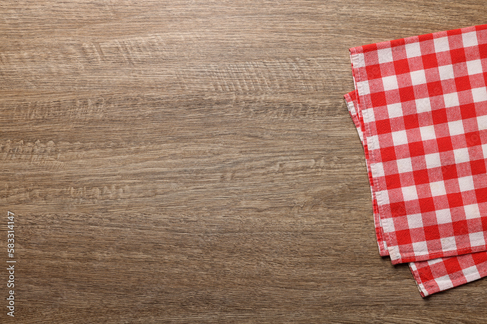 Obraz premium Checkered tablecloth on wooden table, top view. Space for text
