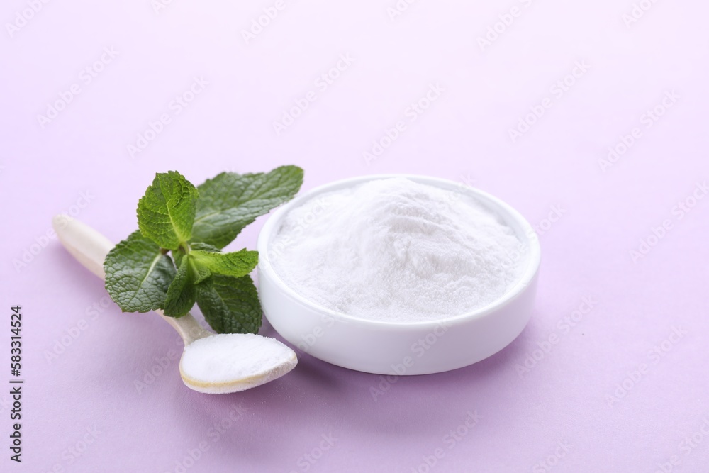 Sweet powdered fructose and mint leaves on light purple background Sweet powdered fructose and mint leaves on light purple background