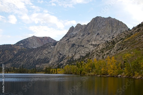 Driving through June Lake loop in the Eastern Sierra  where towering mountains loom overhead and fall colors begin to show on some of the trees at their base. Seen here is Grant Lake.