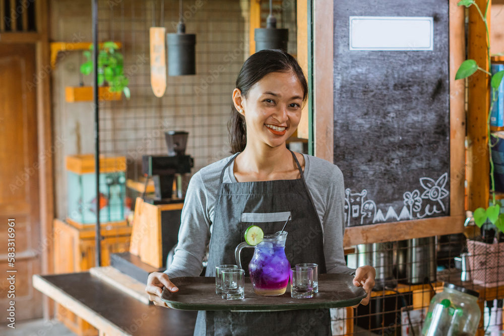 female barista in apron standing with smile while bring the drinks using the tray female barista in apron standing with smile while bring the drinks using the tray