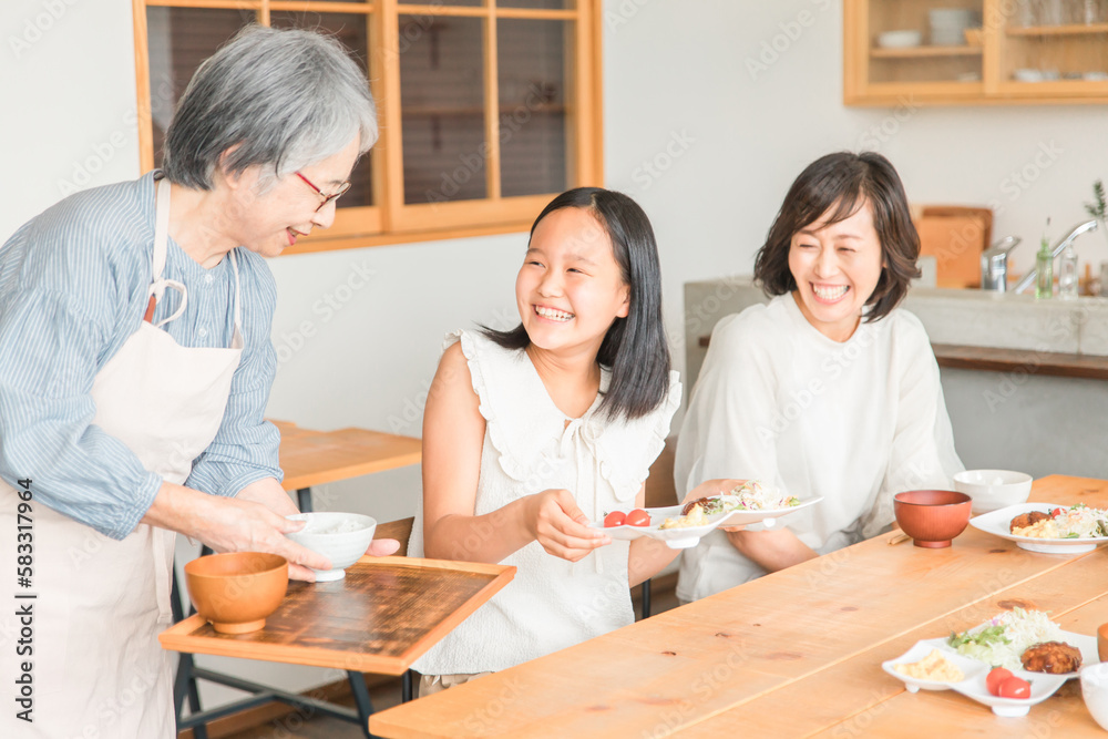 Fototapeta premium 家のダイニングで家族団欒して食事する子供と夫婦・親子・三世代家族(二世帯住宅・帰省・里帰り)