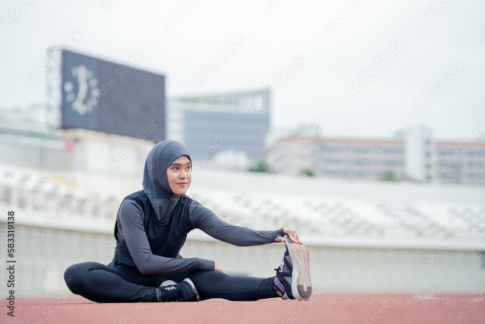 A young asian Muslim woman wearing a black hijab is exercising and running at an outdoor stadium in the morning. Modern Muslim woman concept, Muslim woman sport concept, Islam A young asian Muslim woman wearing a black hijab is exercising and running at an outdoor stadium in the morning. Modern Muslim woman concept, Muslim woman sport concept, Islam