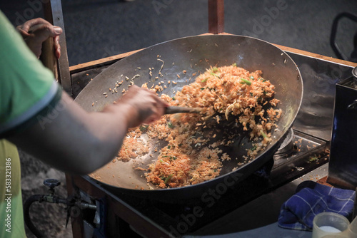 Photography A man cooking fried rice on steel skillet pan for selling on the street food