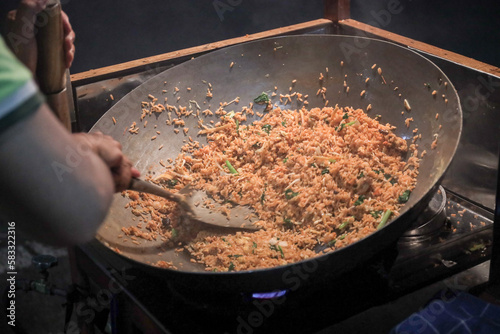 A man cooking fried rice on steel skillet pan for selling on the street food. Indonesian call the dish Nasi Goreng. Indonesian Street food culinary photo