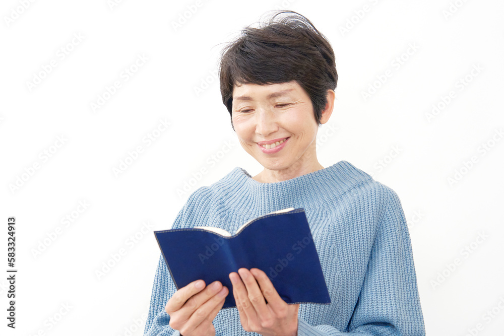 笑顔で読書する中年女性 白背景 笑顔で読書する中年女性 白背景