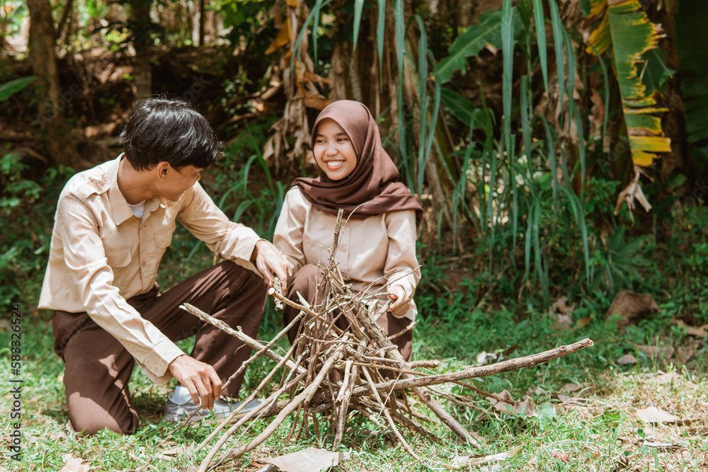 Naklejka premium Girl Scouts and Boy Scouts chat while preparing dry twigs for firewood in nature
