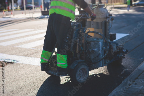 Process of making new road surface markings with a line striping machine, workers improve city infrastructure, demarcation marking of pedestrian crossing with a hot melted paint on asphalt pavement © tsuguliev