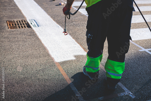 Process of making new road surface markings with a line striping machine, workers improve city infrastructure, demarcation marking of pedestrian crossing with a hot melted paint on asphalt pavement photo
