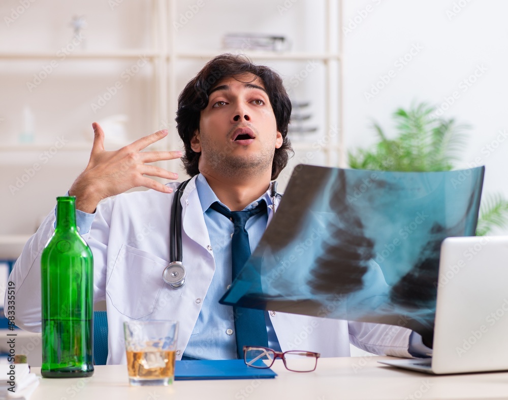 Young male doctor drinking in the office Young male doctor drinking in the office