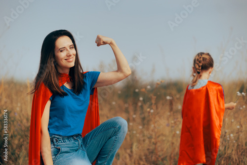 Strong Super Mom Flexing her Muscles Loving her Little Girl. Loving mother and daughter feeling like superheroes together 
