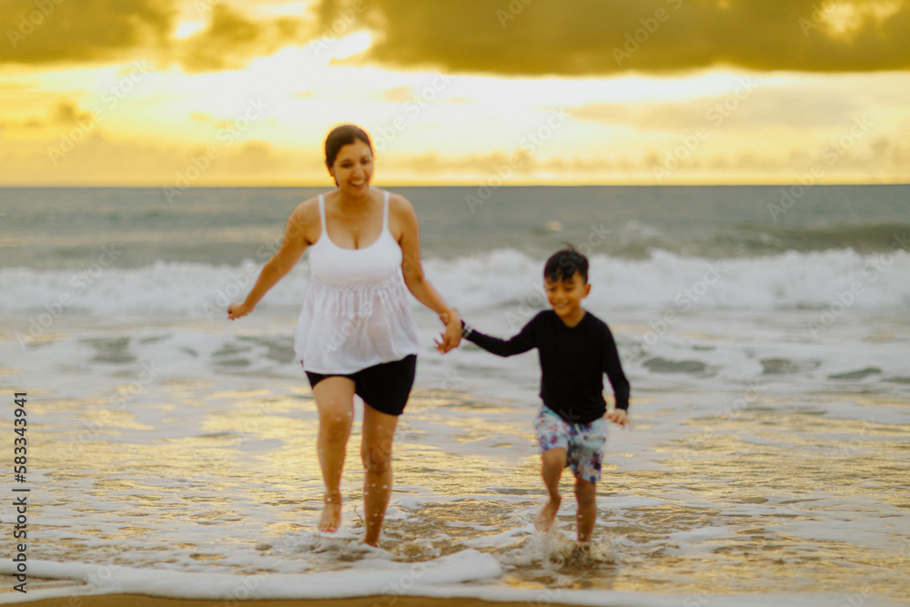 The pregnant woman in the stomach is walking with his first son. Sea by the beach The pregnant woman in the stomach is walking with his first son. Sea by the beach