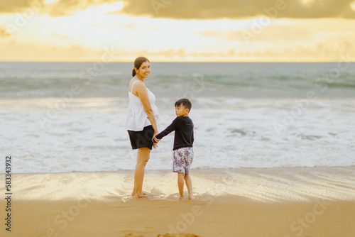 The pregnant woman in the stomach is walking with his first son. Sea by the beach