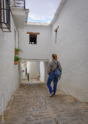 Young white blonde woman dressed in jeans walking through a village in the Alpujarra of Granada © cribea