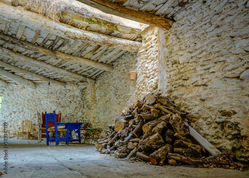 street of a typical town in the Alpujarra of Granada with white walls and a wooden roof and a chair with firewood around it