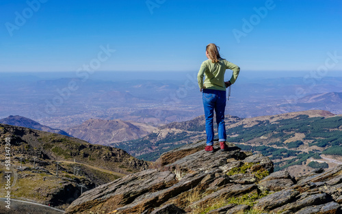 Young Caucasian woman dressed in jeans and sweatshirt enjoying the views of the Alpujarra valleys of Granada photo