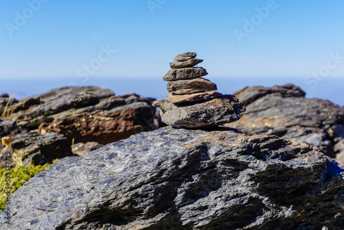 Flat gray stones piled up forming a pyramid and marking the path of a path in the mountains © cribea