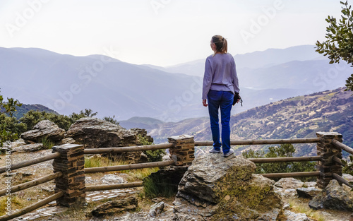 Pretty young woman dressed in jeans and sweatshirt enjoying the landscape of a valley in the Alpujarra of Granada