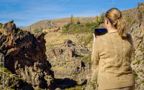 Beautiful young and blonde woman taking photos in a canyon of the Alpujarras region of Granada
