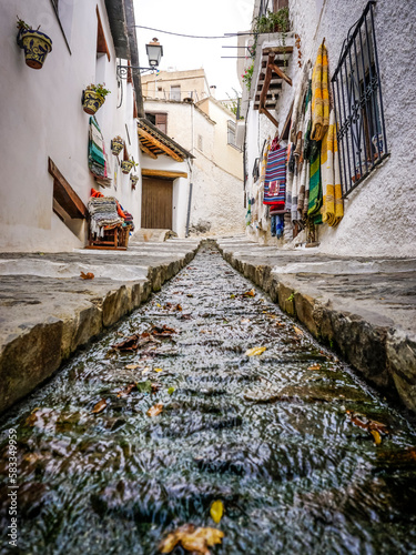 street of a town in the Alpujarra of Granada with water running through a canal in the center of the road © cribea
