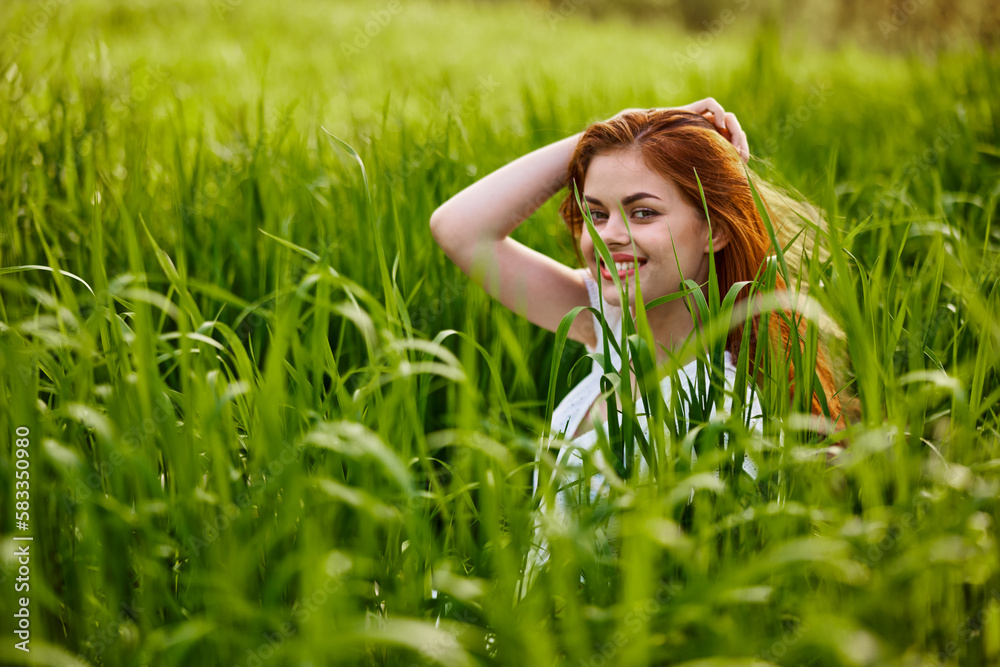 happy woman sitting in tall green grass holding her hair happy woman sitting in tall green grass holding her hair