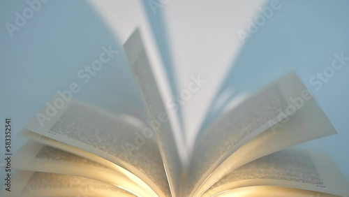 Book with moving pages in the wind with shadows from a spotlight against white background