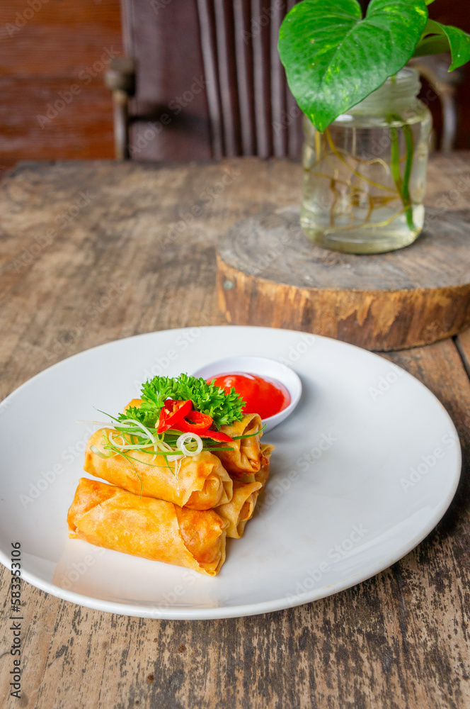 Delicious Asian Snack Spring Rolls or Lumpia Served with Chili Sauce on White Plate