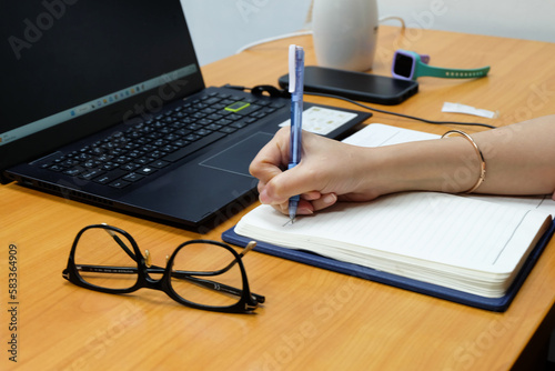 Business woman holding pens and papers making notes in documents on the table